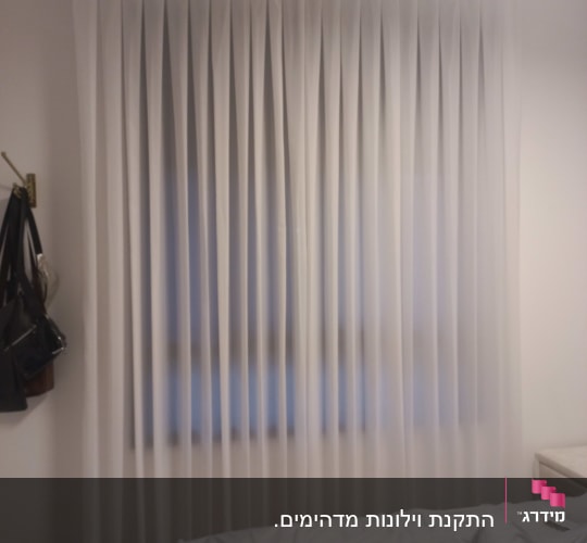 וילון לבן תלוי בחדר שינה עם מיטה